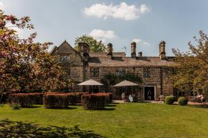 an old stone house with people sitting in the yard at The Peacock at Rowsley in Great Rowsley