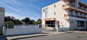 a building with a white fence in front of it at Cit'Hôtel Le Quai 9 , ex Le Challans in Challans