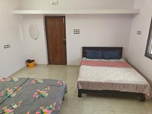 a bedroom with two beds and a wooden door at Treva Breeze Villa 2BHK in Kīl Kāsākkudi