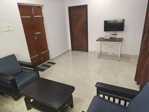 a living room with a chair and a table and a tv at Treva Breeze Villa 2BHK in Kīl Kāsākkudi