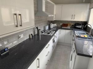 a kitchen with white cabinets and a black counter top at Large Burnley Townhouse in Burnley +21 photos