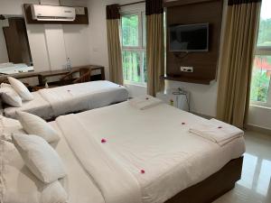 a hotel room with two beds and a flat screen tv at Lilly Ribera in Kumarakom