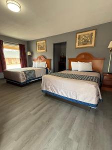two beds in a hotel room with wood floors at Budget Inn in Magnolia
