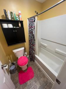 a bathroom with a toilet and a pink stool at Grand Park Spa Getaway in Westfield +7 photos