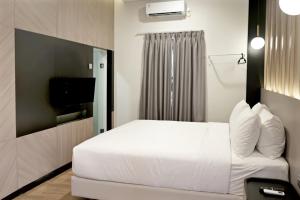 a bedroom with a white bed and a television at Spot 43 Cafe and Hotel in Bandung