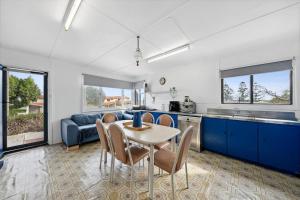 a kitchen with blue cabinets and a table and chairs at Vintage Ledge Point Beach Shack in Ledge Point
