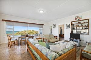 ein Wohnzimmer mit Sofa und Tisch in der Unterkunft The Blue Beach House, 3 star accommodation 5 star view in Ledge Point
