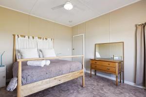 ein Schlafzimmer mit einem Bett, einer Kommode und einem Spiegel in der Unterkunft The Blue Beach House, 3 star accommodation 5 star view in Ledge Point