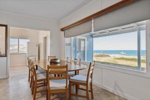 ein Esszimmer mit Tisch und Stühlen und dem Meer in der Unterkunft The Blue Beach House, 3 star accommodation 5 star view in Ledge Point