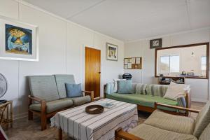 ein Wohnzimmer mit Sofa und Tisch in der Unterkunft The Blue Beach House, 3 star accommodation 5 star view in Ledge Point + 22 Fotos