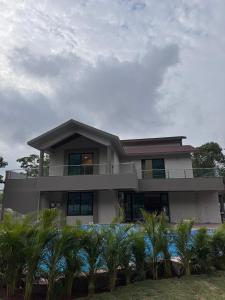 a house with palm trees in front of it at Bhargavi Villa in Kolvan