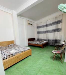 a bedroom with two beds and a table and a chair at Motel Hoàn Chun in Can Tho