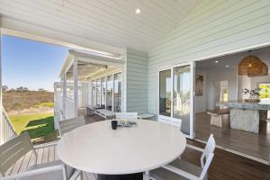 a dining room with a white table and chairs on a porch at Stunning Lookout Lancelin in Lancelin