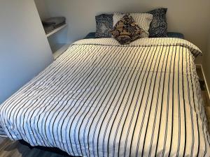 a large bed in a bedroom with a striped bedspread at Modern villa apartment with free parking in Sollentuna