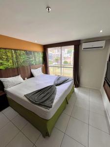 ein Schlafzimmer mit einem Bett und einem großen Fenster in der Unterkunft ApartHotel Centro de Nova Iguaçu in Nova Iguaçu + 7 Fotos
