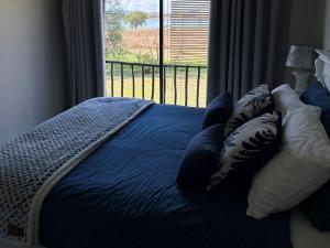 - un lit avec des draps et des oreillers bleus et une fenêtre dans l'établissement Vaal Dam Getaway, à Denysville