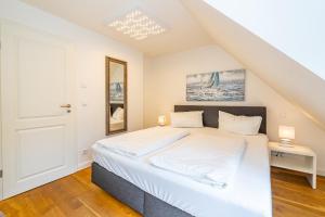 a bedroom with a bed with white sheets at Gode Stuv in Westerland