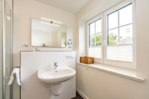 a white bathroom with a sink and a mirror at Gode Stuv in Westerland +27 photos
