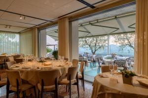 a dining room with tables and chairs and large windows at Hotel Ristorante La Rosina in Marostica
