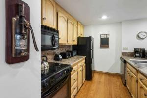 a kitchen with wooden cabinets and black appliances at Lodge Tower 487 Three Bedroom Residence in Vail