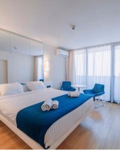 a bedroom with a large bed and two blue chairs at Orbi City SGC in Batumi