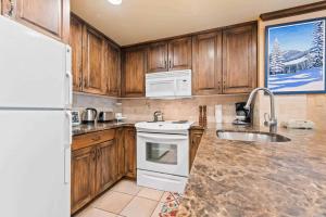 a kitchen with wooden cabinets and a white stove top oven at Lodge Tower 494 One Bedroom Residence in Vail