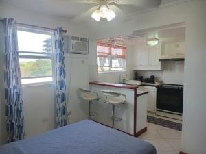 a kitchen with a counter and two stools at Alleyne Apartments in Bridgetown