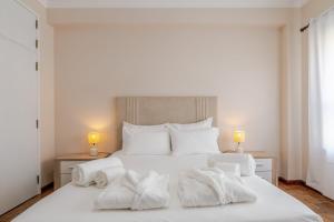 een slaapkamer met een wit bed met handdoeken erop bij White Charm by the Sea in Viana do Castelo