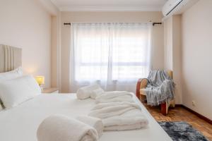 een slaapkamer met een wit bed met handdoeken erop bij White Charm by the Sea in Viana do Castelo