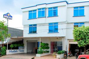 a white building with blue windows on a street at HOTEL TANIA in Caucasia