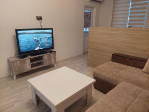 a living room with a flat screen tv and a couch at Двушка для гостей in Baku