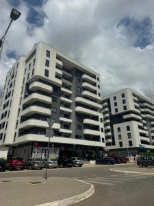 two large white buildings with cars parked in a parking lot at Lux stan in Bar