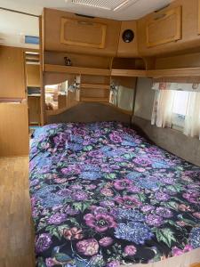 a bed in the back of an rv with a floral blanket at Tornio caravan in Tornio