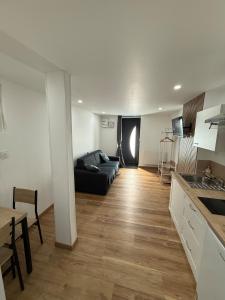a living room with a black couch and a kitchen at Chaleureux Studio Tout Confort in Orléans