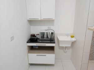 a small white kitchen with a sink and a counter at Apartamento tipo kitnet mobiliado in União dos Palmares +3 photos