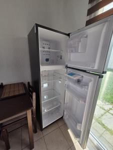 een lege koelkast met de deur open naast een tafel bij The terrazzo house in Santa Ana