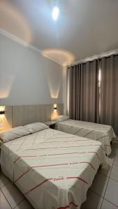 zwei Betten in einem Hotelzimmer mit weißer Bettwäsche in der Unterkunft Hotel Salomão - Próximo a 25 de Março, Bom Retiro, Brás e Rua Santa Efigênia, a 2 minutos do Mirante Sampa Sky e pista de Skate Anhangabaú in São Paulo + 79 Fotos