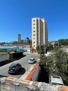 two cars parked on a street with a tall building at recanto da basílica in Aparecida