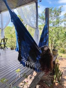 a woman laying in a hammock on a deck at Casa Contêiner imersão com Natureza Floresta Sapiranga-5km praia do forte in Mata de Sao Joao