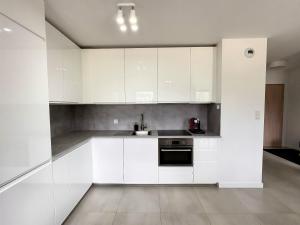 a kitchen with white cabinets and a sink at Baltic Spot Apartment Letnica in Gdańsk