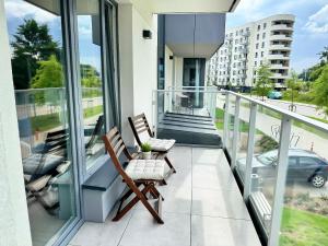a balcony with two chairs and a view of a building at Baltic Spot Apartment Letnica in Gdańsk