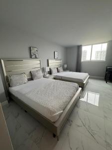 a bedroom with two beds and two windows at Spacious Apt Ocean Reserve Resort Amenities in Sunny Isles Beach