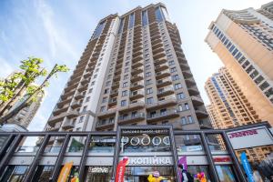 a tall building with a sign in front of it at Rodos ArCadia Apartments in Odesa