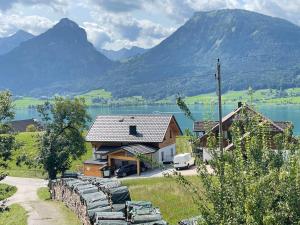 a house with a row of chairs in front of a lake at Mountains & Lake Boutique Apartment in St. Wolfgang