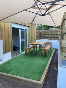 a picnic table and benches under an umbrella on a patio at L'orangerie in Seignosse +4 photos