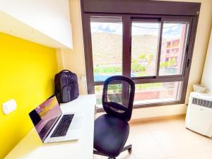 a desk with a laptop and a chair next to a window at Little Palmar with Free Parking & Pool & Padel in Palm-Mar