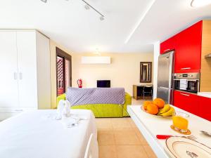 a kitchen and living room with red cabinets and fruit on a table at Little Palmar with Free Parking & Pool & Padel in Palm-Mar +15 photos