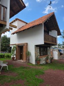a white house with a porch and a balcony at Cabañas Las orquídeas in Huasca de Ocampo