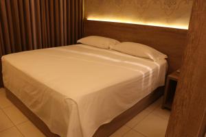 een bed met witte lakens en kussens in een kamer bij Indaiá Park Hotel in Campo Grande +95 foto's