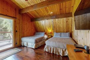 two beds in a room with wooden walls and wood floors at Primrose Cabin #709 in Big Bear Lake